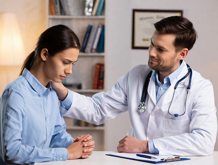 Врач-мужчина утешает обеспокоенного пациента, кладя руку на плечо для поддержки